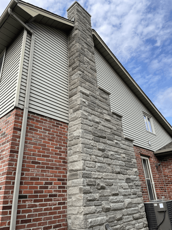Existing red brick chimney before replacement and exterior paint integration on a white brick home in London Ontario